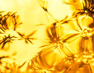 Abstracte afbeelding van golvend, goudkleurig water met schaduwen van bloemen en bladeren.