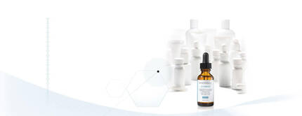 Flesje serum met pipet op een witte achtergrond met wazige flessen erachter.