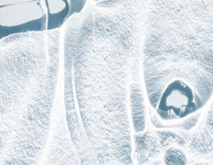 Abstract close-up of ice, showcasing intricate textures and patterns formed by freezing and reflections.