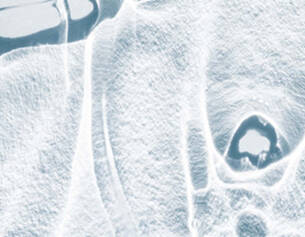 Abstract close-up of ice, showcasing intricate textures and patterns formed by freezing and reflections.