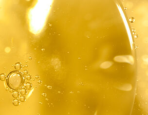 Close-up van gouden olie met luchtbellen die omhoog stijgen, waardoor een glanzend en vloeiend effect ontstaat.