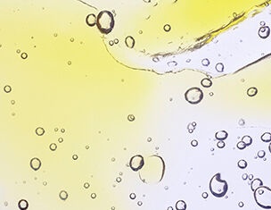 Bubbles rising in a translucent liquid with a gradient of yellow to clear, creating an abstract, fluid appearance.