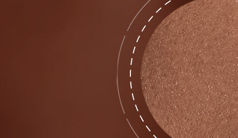 Close-up of a textured, warm brown surface with a shimmering, circular highlight on one side.