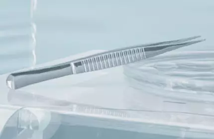 Close-up of a sleek dental instrument and a transparent dental tray, set against a soft blue background.