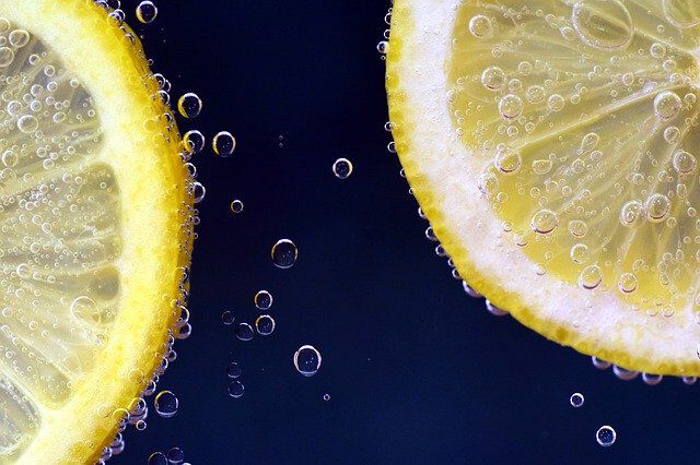 Close-up of two lemon slices submerged in sparkling water, with small bubbles clinging to the fruit.