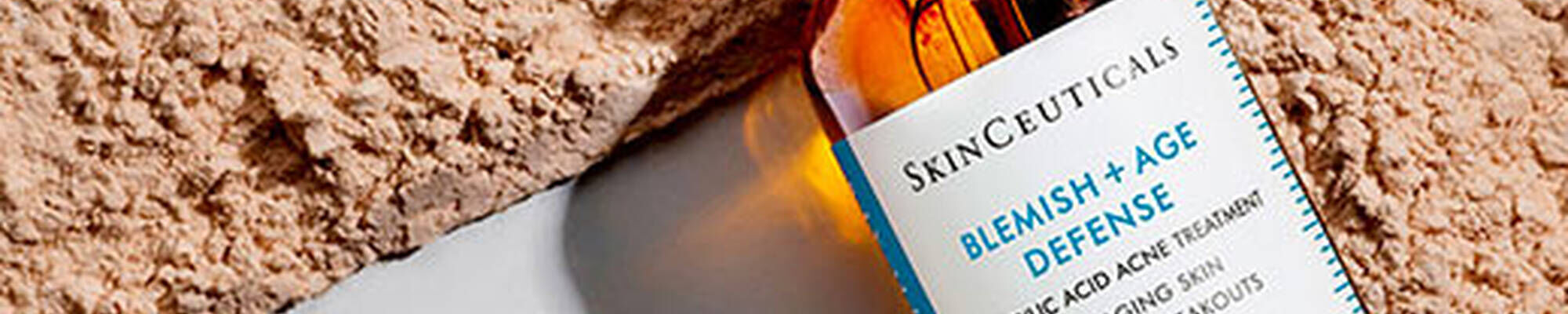 Flesje SkinCeuticals Blemish + Age Defense serum ligt op een lichte, ondergrondse textuur.