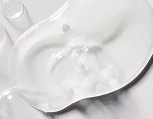 Duidelijke gel die op een witte achtergrond ligt, met een organische, vloeiende vorm en enkele luchtbelletjes.