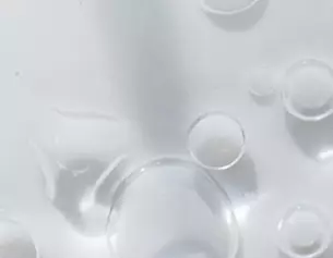 Druppels water zweven op een gladde, witte ondergrond, met verschillende formaten en helderheid.