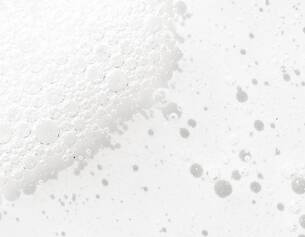 Close-up of white foam with bubbles, creating a textured surface on a light background.