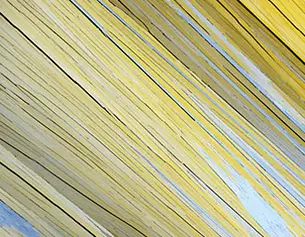 Close-up of textured yellow and gray wooden planks angled diagonally, creating a dynamic visual pattern.