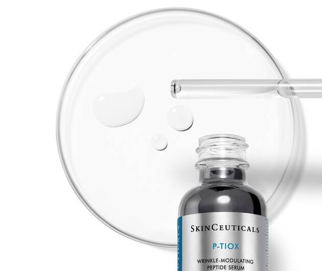 Een flesje SkinCeuticals P-TIOX serum met druppels op een petrischaal, voor een anti-aging effect.