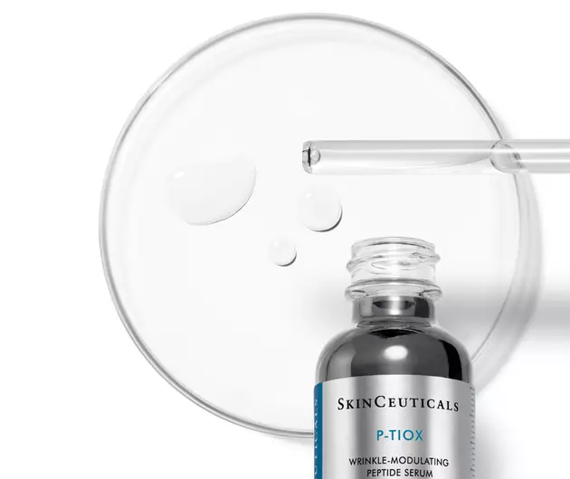 Een flesje SkinCeuticals P-TIOX serum met druppels op een petrischaal, voor een anti-aging effect.