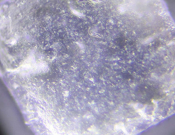 Close-up van een helder kristal met fijne bubbels en een sprankelende oppervlakte.