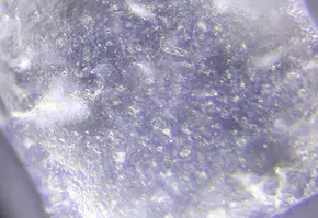 Close-up van een helder kristal met fijne bubbels en een sprankelende oppervlakte.