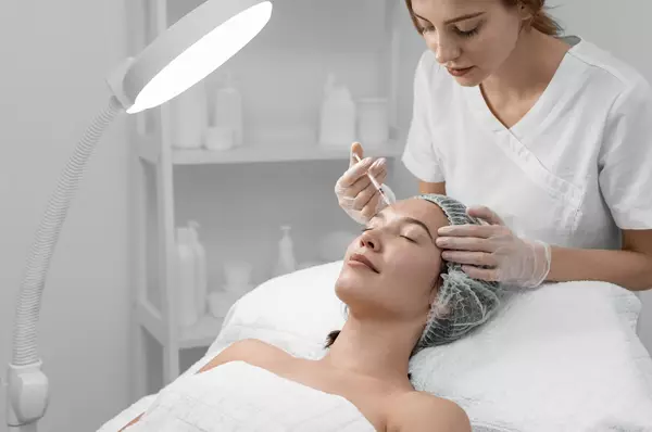 Een vrouw krijgt een schoonheidsbehandeling van een schoonheidsspecialiste in een moderne spa-omgeving.