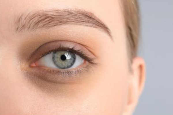 Close-up van het oog van een vrouw met een heldere, groene iris en een neutrale huidtint.