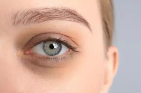 Close-up van het oog van een vrouw met een heldere, groene iris en een neutrale huidtint.