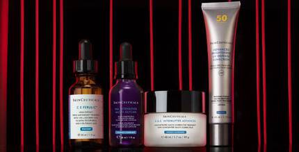 Drie flessen en een potje met huidverzorgingsproducten op een witte achtergrond.