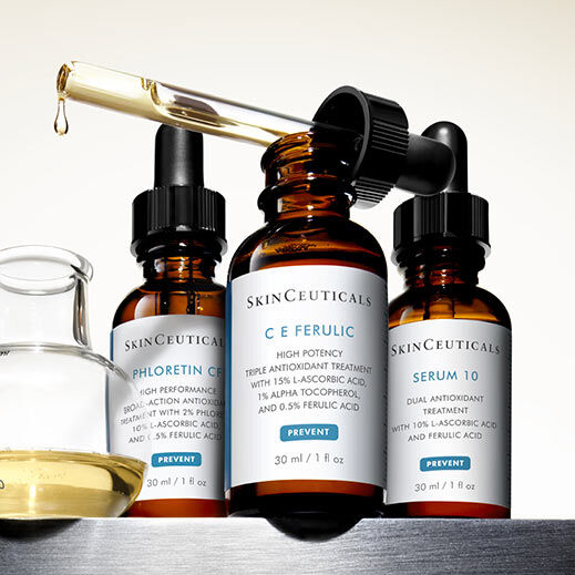 Drie flessen met huidverzorgingsserums van SkinCeuticals, waaronder C E Ferulic, Phloretin CF en Serum 10, staan op een schap met een pipet en een glazen houder.