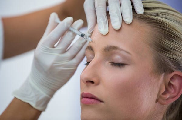 Een vrouw ondergaat een cosmetische behandeling met een injectie in het voorhoofd.