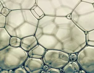Een close-up van zeepbellen met een abstracte structuur van hexagonale en ronde vormen.