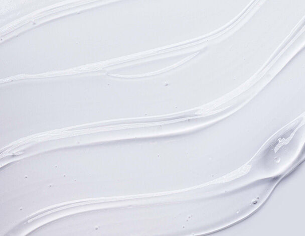 Swirls of creamy white texture on a smooth background, resembling skincare or cosmetic product application.