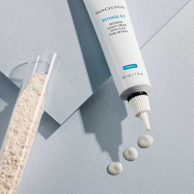 A tube of SkinCeuticals Retinol 0.3 night cream, with a small amount of cream squeezed out, is displayed beside a transparent vial of white powder on a light blue background.