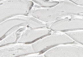 Close-up van glanzende, transparante gelachtige textuur met golvende lijnen op een witte achtergrond.