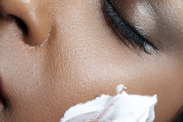 Close-up van een vrouw die gezichtscreme aanbrengt op haar gezicht.