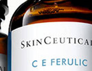 Drie glazen flessen SkinCeuticals C E Ferulic serum met een klein glasnetje ernaast.